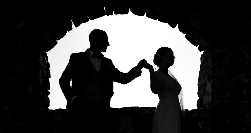 Silhouette de couple de mariés au Beausset, se tenant la main sous une arche en pierre.