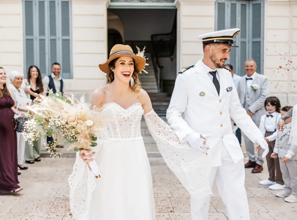 Sortie de la mairie du Beausset : la mariée souriante avec un chapeau et le marié en uniforme de marine.