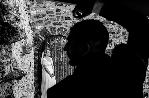 Photo de mariage artistique au Beausset : silhouette du marié regardant la mariée dans une arche en pierre.