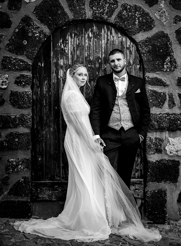 photographe-mariage-beausset-evenos-var Mariage au Beausset : couple de mariés posant en noir et blanc devant une porte voûtée en pierre.